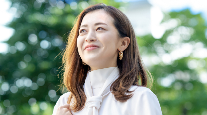 女性が自然光の中で微笑む様子。ツヤのある髪と柔らかな表情が印象的。