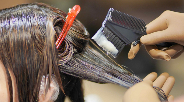 美容師がヘアカラー剤を塗布する施術シーン。丁寧にカラーを入れるプロフェッショナルな技術を表現。