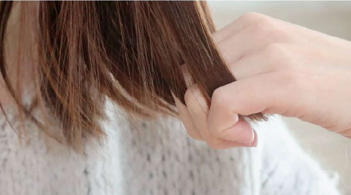 毛先を指で確認する様子。ダメージケアやトリートメント前後の質感チェックをイメージ。