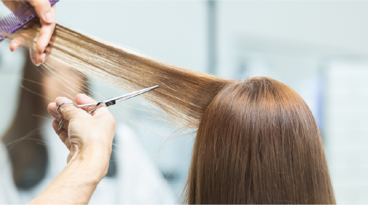 美容師がハサミで髪をカットする様子。正確で繊細な技術による美しいヘアデザインの施術シーン。